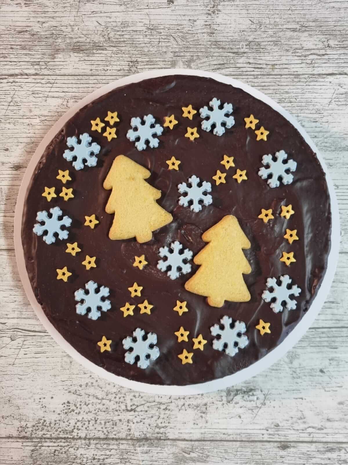 Chocoladetaart met koekjes in de vorm van kerstbomen, sneeuwvlokken en sterren
